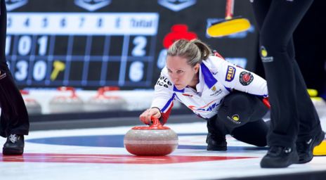 Female curler shooting the stone on the curling sheet